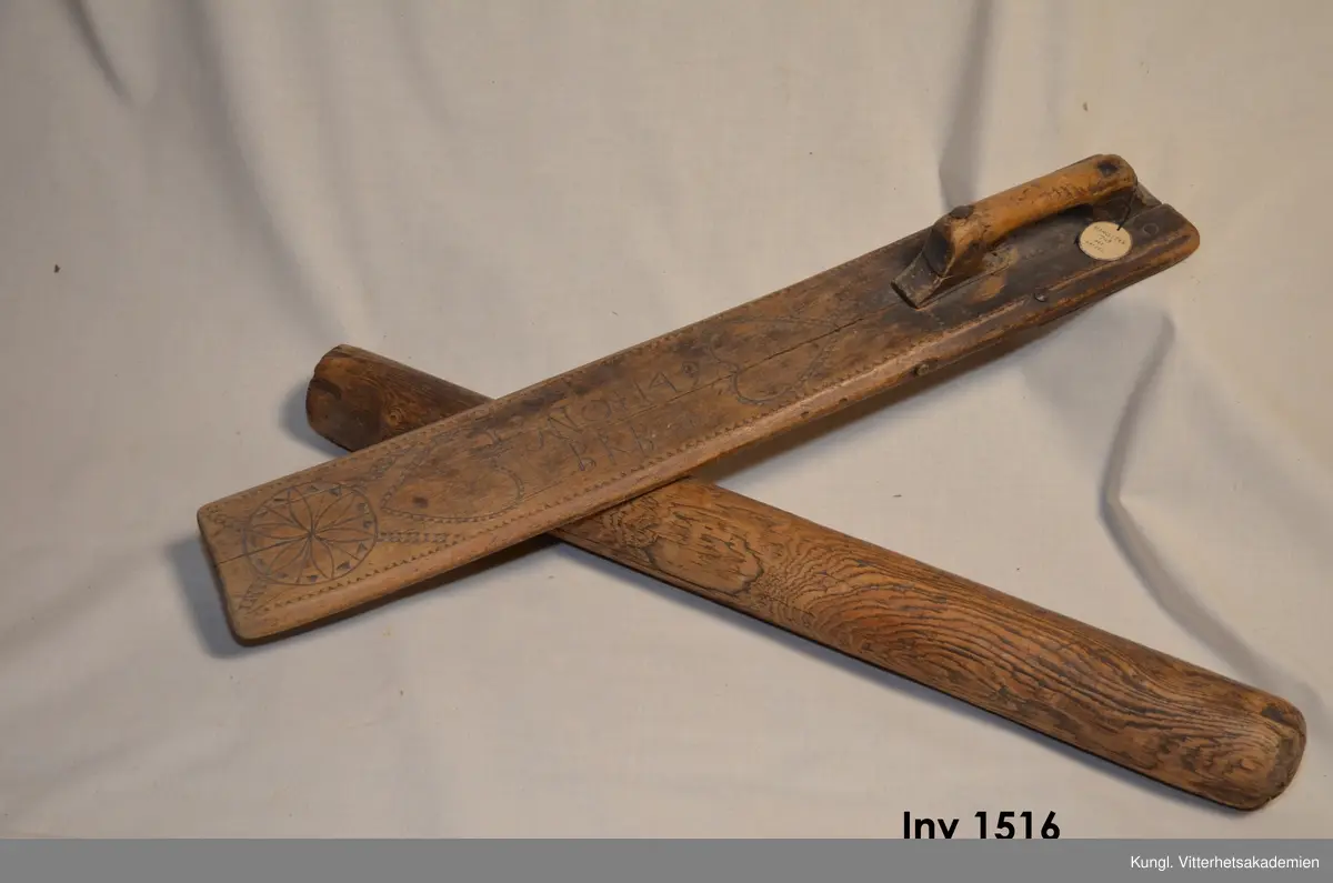 Mangelträ av ek, färg brun rist. o. karvsnittorn med tillhörande kavel. Utmed kanterna karvsnitt. Två motställda hjärtan i karv och ristornering antyder fästmansgåva. dat. 1749 B R B. På undersidan av mangelträet, under handtaget, sitter en påspikad plåtbit som förstärkning och fastsättning av handtaget. Även en genomgående plugg antyder att mangelträet har använts flitigt under lång tid och genom diverse reparationer kunnat brukas ytterliger en tid.

fr. Uslamit Films sn. Uppland