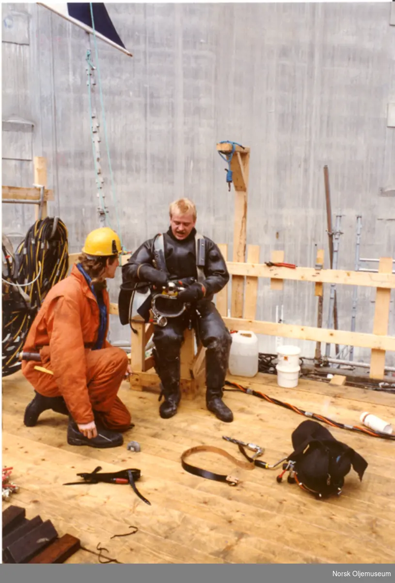 Ekofisktank-veggen klargjøres i Ålsfjorden. Dykkerne arbeidet for Amundsen Diving. Dykker i tørrdrakt og blybelte. Jobben var å feste ting på veggen. 