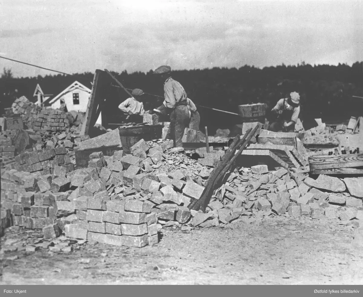 Huggeplassen i stenbrudd - storbruddet på Greåke i Tune 1920. Utsnitt: Fire stenhoggere bearbeider sten i storbruddet på Greåker.
Krana på kanten av "Høla". Produksjon av småsten (gatesten/kantsten)