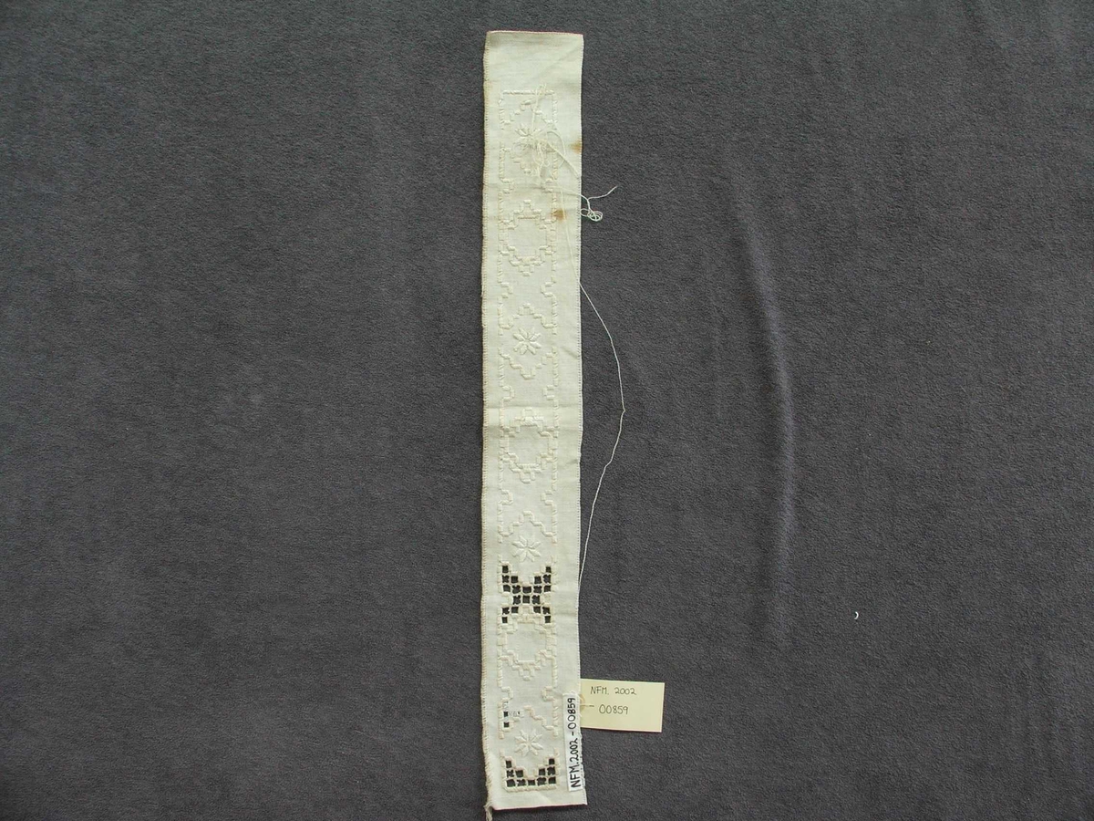 Byrjinga på broderi. Kvitsaum, holsaum. Ein kan sjå korleis holsaumen er gjort.