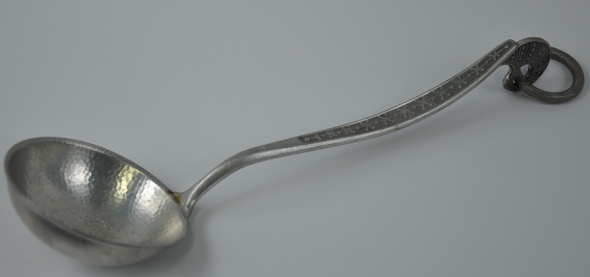 Skaftet på ausa har eit dekorfelt som er oksydert og eit mønster av samanhengjande prikkar og stjerner. Stjernene vert større der skaftet er breidast. Opphenget på skaftet har eit prikk- og stripemønster.