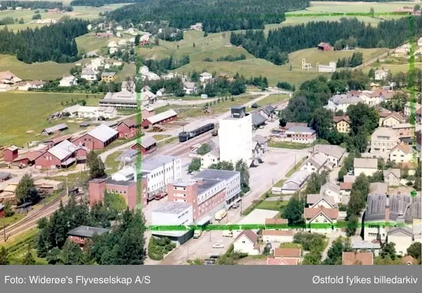 Skråfoto av Rakkestadbyen, 13. juli 1964.

Rakkestad meieri og iskremfabrikk og Rakkestad sag og Høvleri på hver sin side av jernbanestasjonen midt i bildet.
Rakkestad eggsentral, "eggsentralen" på folkemunne, bak til venstre.
Trafo stasjon i bakgrunnen til høyre.