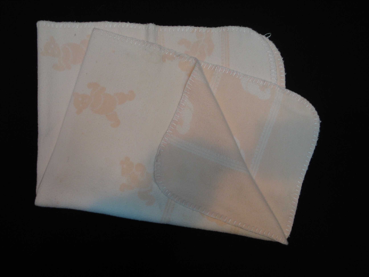 Teppet er kvitt på den eine og rosa på den andre sida. På den rosa sida er kvite bamsar, på den kvite sida er rosa bamsar.