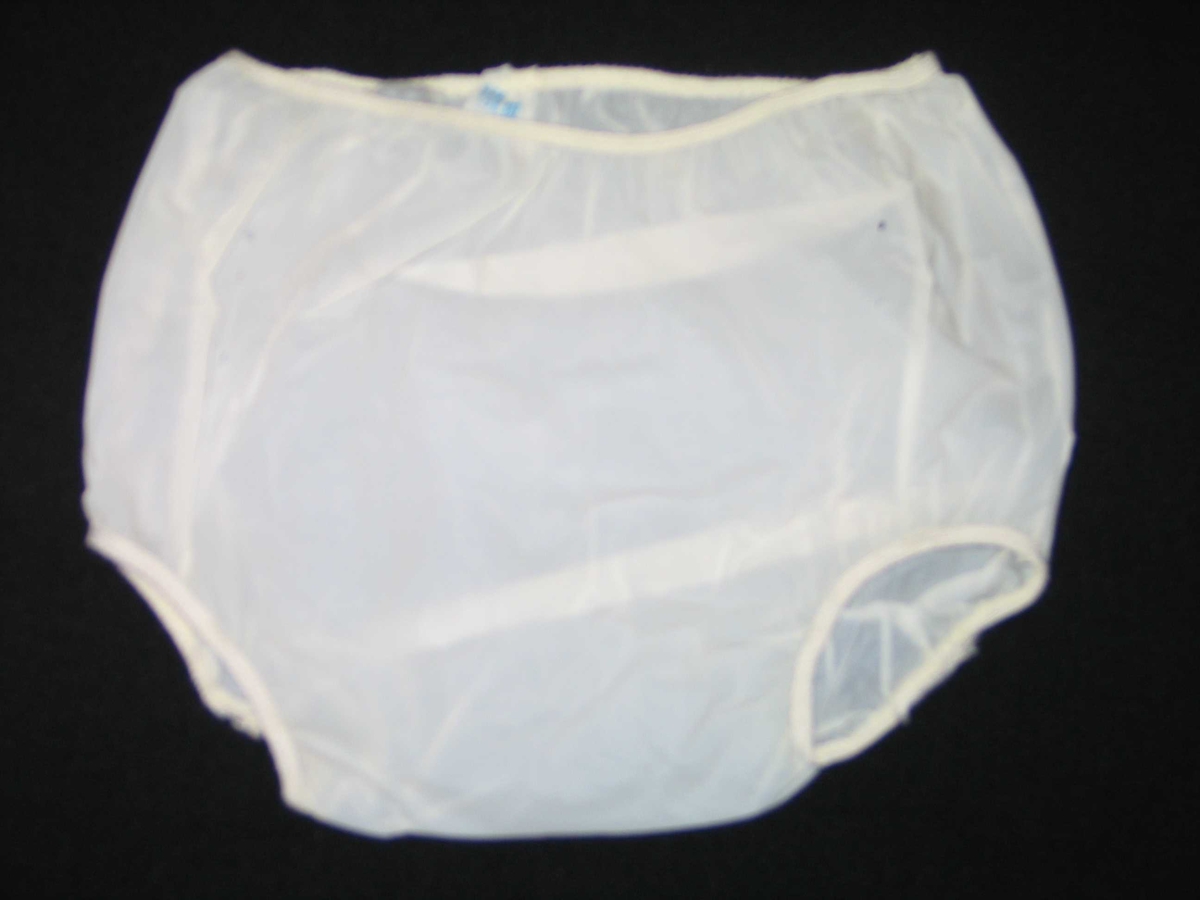 Bukse av plast. Utanpåsydd strikk i livet og rundt låra.
Luftehol i sidene. Skal trekkajst utanpå bleier av flanell eller papir.