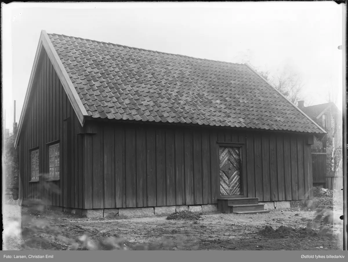 Borgarsyssel Museum, husmannsstue, eksteriør, oppført på museet 1934.
Husmannsstua var opprinnelig en plass under Hafslund hovedgård i Skjeberg, den hette Nesset. Stua var bygd på midten av 1800-tallet, og var stor til å være en husmannsplass, den var en såkalt bruksarbeideplass.

I bakgrunnen skimtes en av ingeniørboligene til Borregaard som lå i Borregaardsveien, denne er nå revet. (Omtrent der Wegenerbrakka ligger i dag).