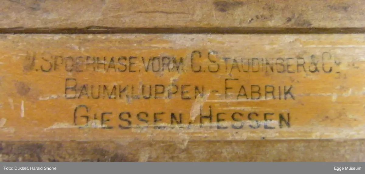 Taksasjonsklave laget av ukjent tresort. Linjal er tappet inn i fast arm. På toppen av fast arm er det påsatt en tynn treplate. Skyvbar arm er tappet inn i kloss som kan beveges opp eller ned og skrus fast i ønsket posisjon med en vingeskrue på baksiden. Klossen er limt og stiftet sammen av flere deler. Linjalen har skrå sider. Cm måleskala fra 1-50. Tallene er trykt inn.
