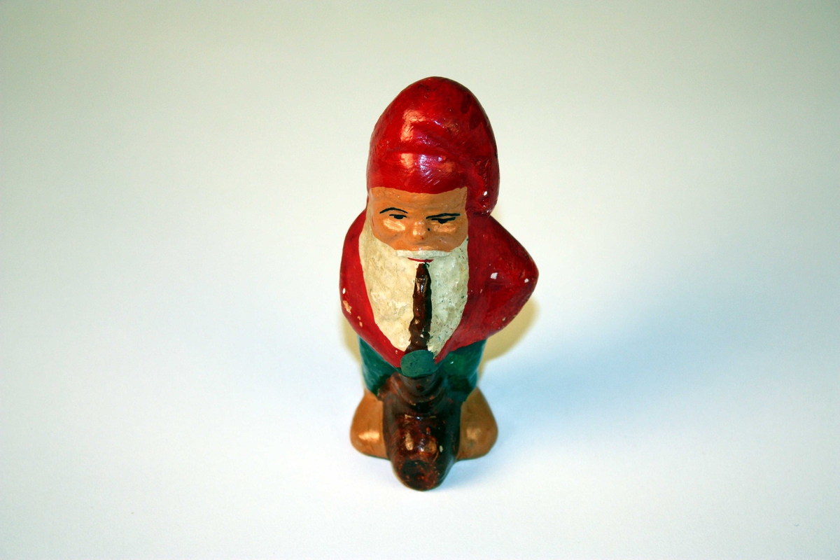 Nisse som står og røyker på ei fotsid pipe.