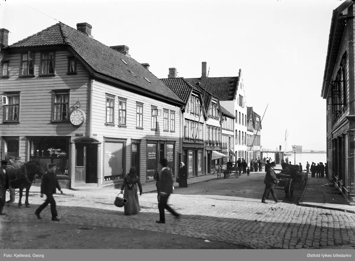 Gateparti fra Stavanger, hjørnebygningen er Breigata 20. 

Vindusreklame i hjørnebygning:
Halvorsens Uhrforretning, med veggur.
Andreas Helland. Kolonial, Korn, Mel & Fedevareforretning.