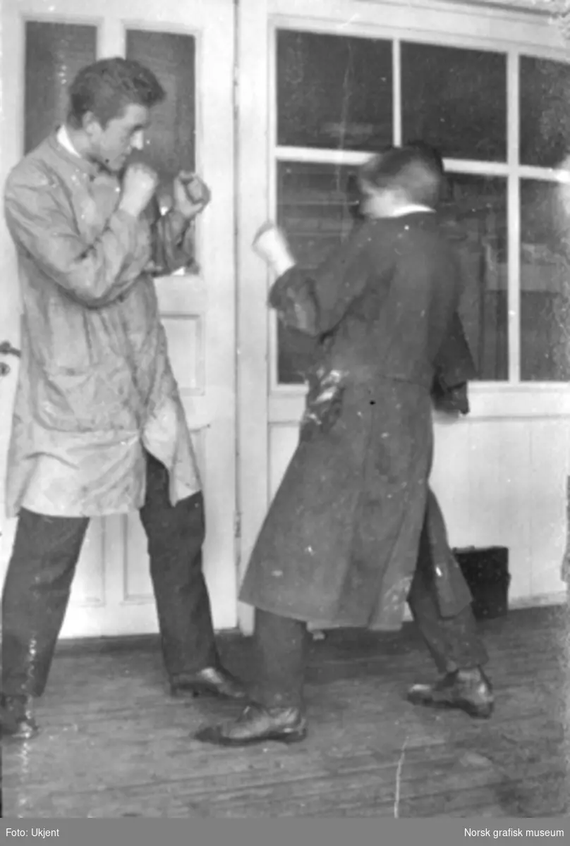 To unge menn i boksepositur for kameraet. Innendørs på Dreyers Reproduktionsanstalt i Stavanger. Tekst under bildet i albumet: "Ungdom 1919. Naar de andre er ute"