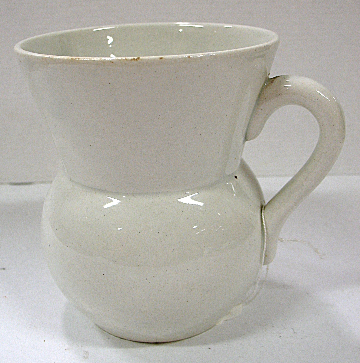 Host och spottekoppen har rund buk, uppåtvidgad hals, handtag.