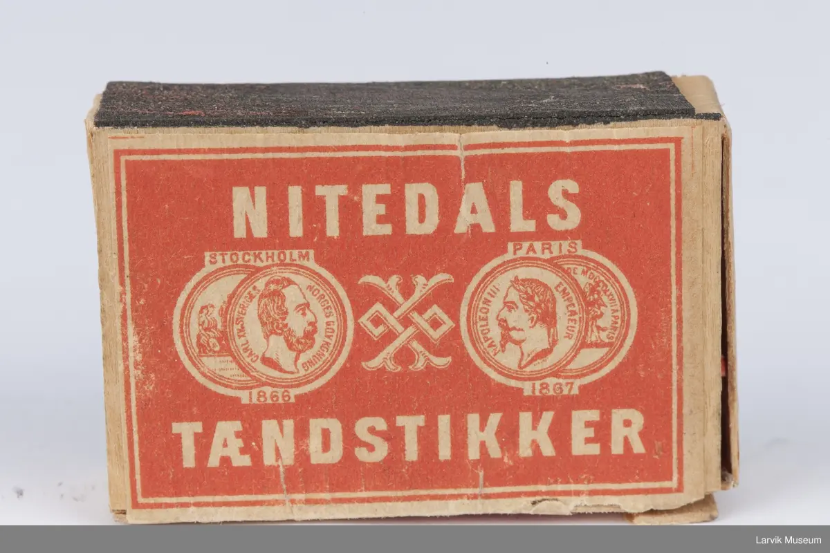 På lokket tekst og 2 mynter på hver side av et ornament med 