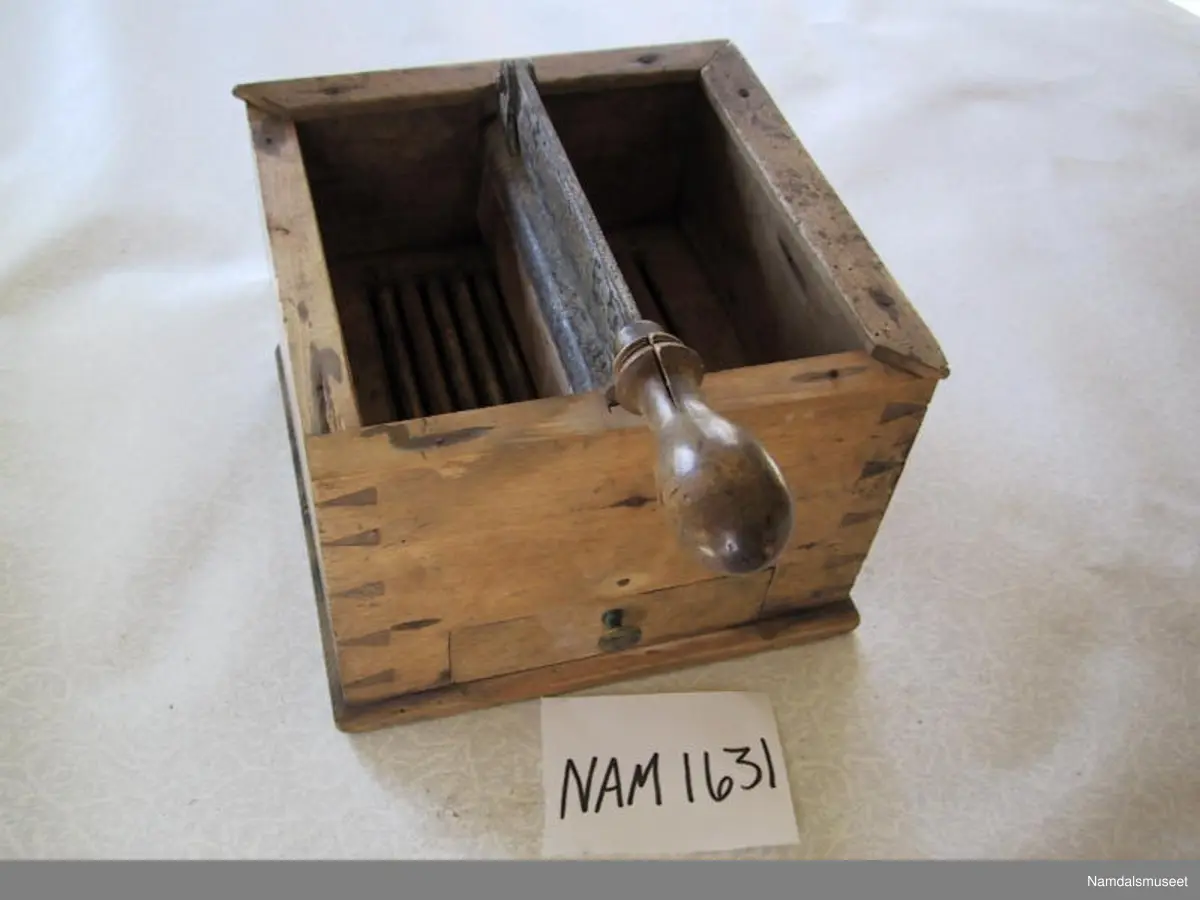 Teknikk: Sinket trekasse med skuffer. Lister på oversiden. På en jernbeslått midtstolpe er hengslet en kniv med trehandtak.
Avdelt med trerist og skuffe under.
Form: Kvadratisk kasse.
