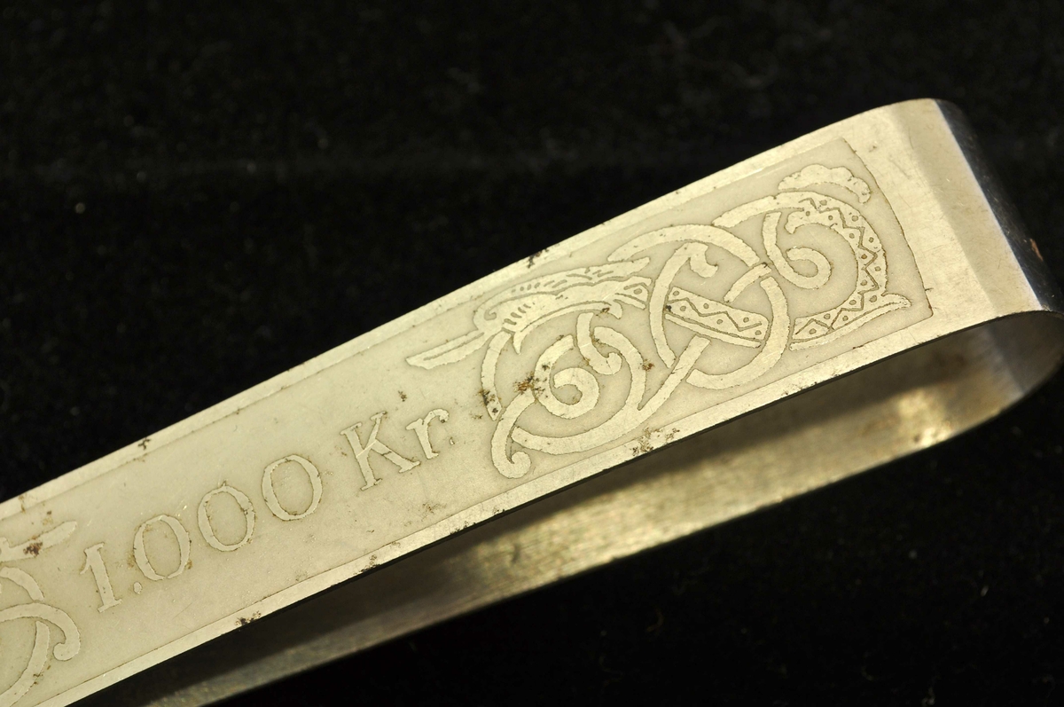 Beløpet "1.000 Kr." på den ene siden. Buktende drageskikkelser til høyre og venstre for beløp, og på den andre siden.