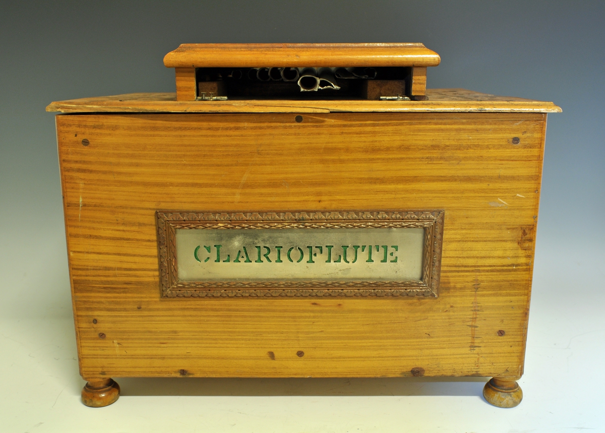 Lirekasse med sveiv - navneskilt foran "CLARIOFLUTE". Tilhørende tinn-plater med musikk på, se TGM.2011:0313.