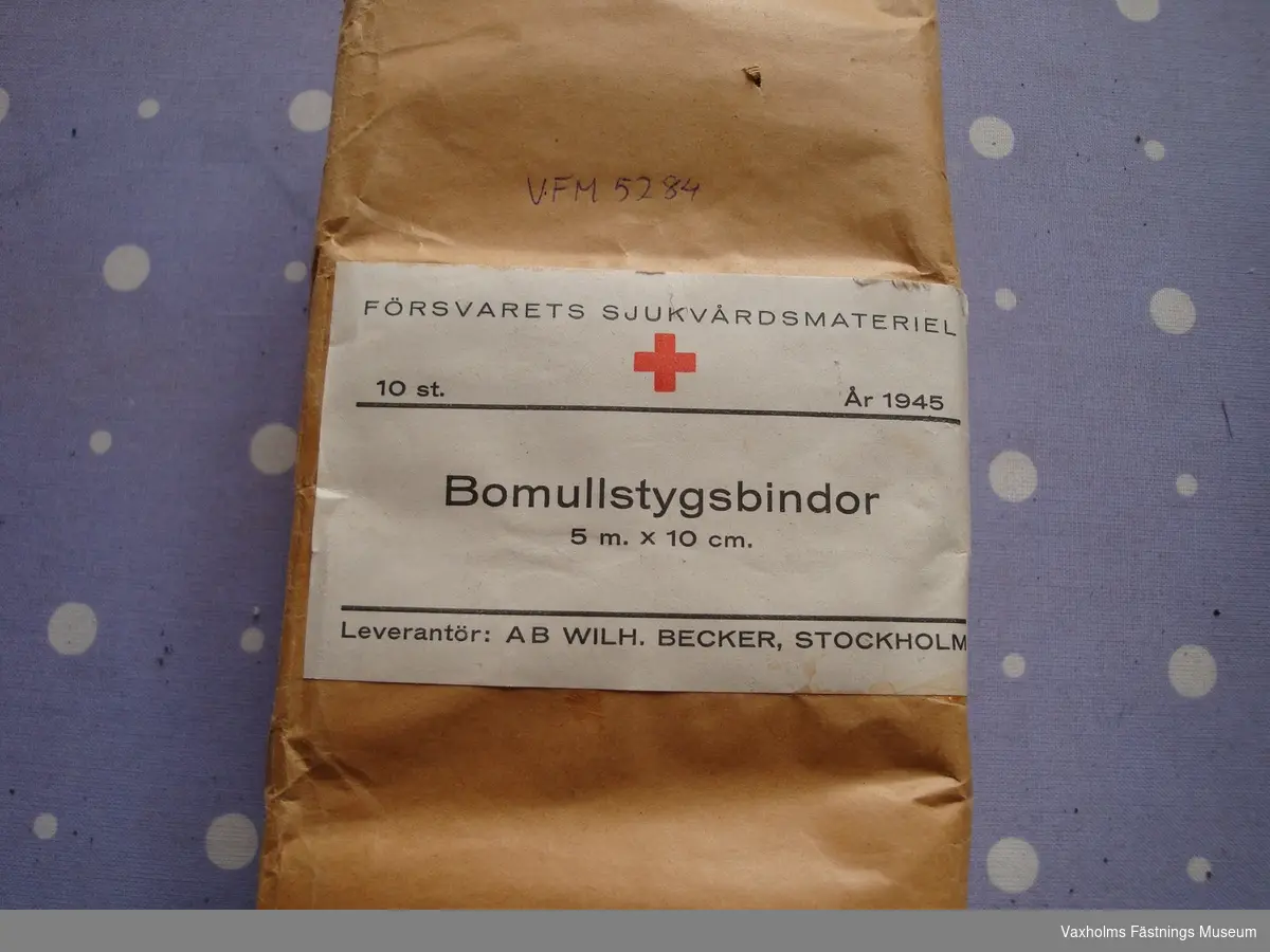 Sjukvårdsmateriel från andra världskriget. Förbandspaket, bomullstygsbindor och kompresser. Leverantörer: Ernst Rudels AB Stockholm, AB Wilh Becker, kunglig hovleverantör Stockholm och Apotekarnas kemiska laboratorium AB Stockholm.