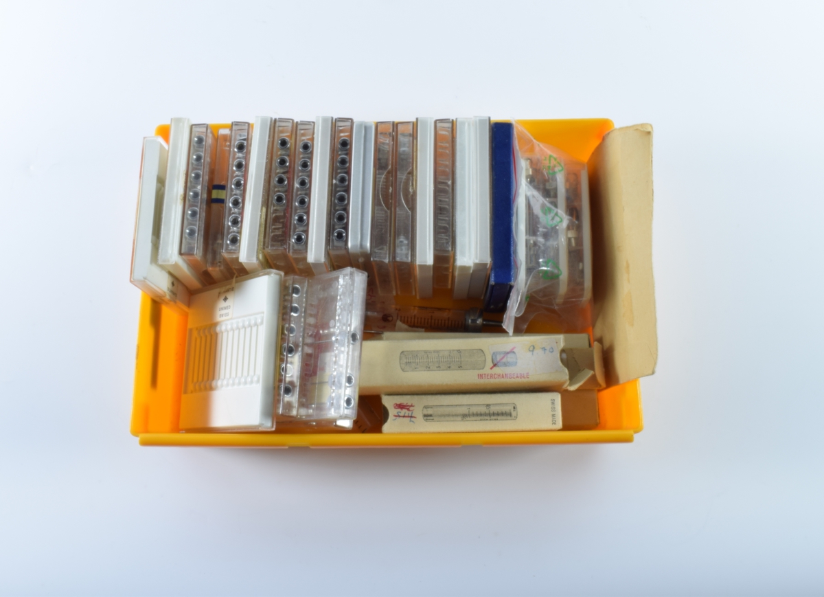 Oransje, rektangulær, plasteske uten lokk som inneholder diverse kanyler og sprøyter. 

Det er 22 kvadratiske, flate esker med kanyler i stål. 20 av eskene er av plast, hvorav 12 er i klar plast og 8 er i hvit plast med skyvelokk i klar plast. En eske er av metall og en er av papp. Antallet kanyler i eskene varierer og de er av forskjellig størrelse. Det er også tre mindre esker i plast med hvit lokk som inneholder 6 kanyler hver. En lang kanyle ligger løs.

Det er fire esker i hvit papp som inneholder hver sin sprøytesylinder uten stempel. Sprøytesylinderene er av plast. Tre er av ensartet størrelse (10cm lang eske), mens den fjerde er litt mindre (8 cm lang eske). En sprøytesylinder av glass med metallbeslag i begge endene ligger løs.

Den oransje esken inneholder også en brun papirkonvolutt med 11 bunter tynne metalltråder. På konvolutten står det "Rensenåler".