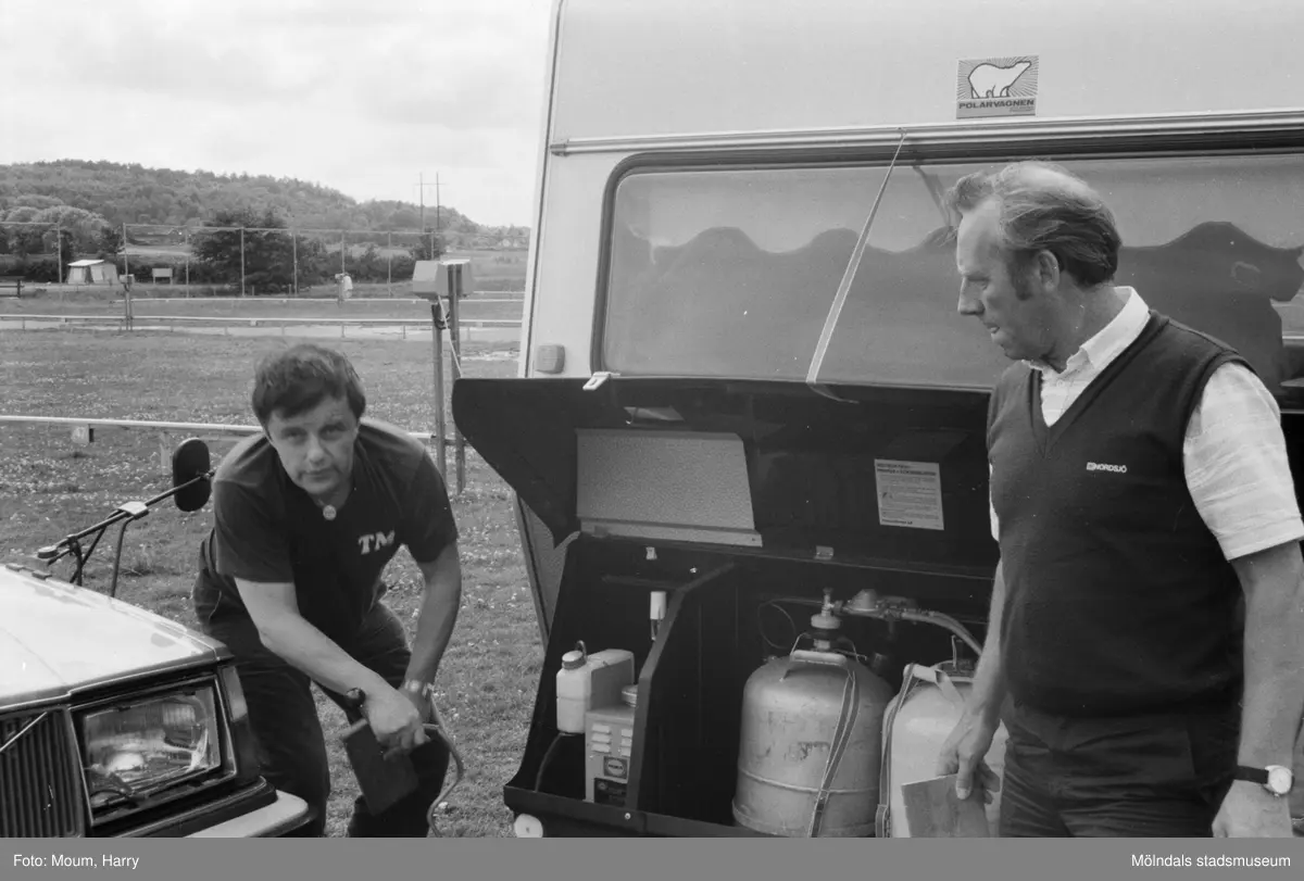 Campare vid Åby camping i Mölndal, år 1984. "- Vi håller på att greja med strömtillförsel, gasol och mat, skrattar äktaparen Mortensen från Tromsö och Myrbakk från Fredrikstad.
- Och jag har gjort misstaget att kontakta mitt företag på första semesterdagen, säger Torbjörn Myrbakk. Affärsvänner från Japan väntar där hemma, så jag får ta första flyget till Norge och sedan via flyg försöka hinna ifatt de andra i Köpenhamn."

För mer information om bilden se under tilläggsinformation.