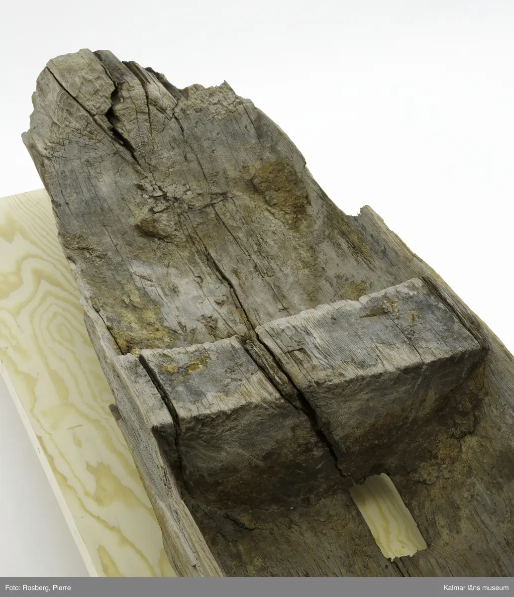 KLM 9303. Båt, stockbåt. Av urholkad trädstam. Huggen i ett stycke. Den har subrektangulärt tvärsnitt, dvs. rektangulär form med rundade kanter. Båten är formad med ett mittre djupare rum med högre för- och akterpartier. Mittpartiet är avgränsat med vertikala tvärväggar, skottar, som utgörs av den bibehållna stocken. Den bakre tvärväggen är högre och har troligen använts som toft. I aktern en köl som sträcker sig fram till ungefär mitten av båten. Framför tväravsatsen i aktern, toften, finns babord om kölen ett rektangulärt hål 15 x 6 cm i botten. På båten en beläggning, troligen sediment från sjön den hittades i.