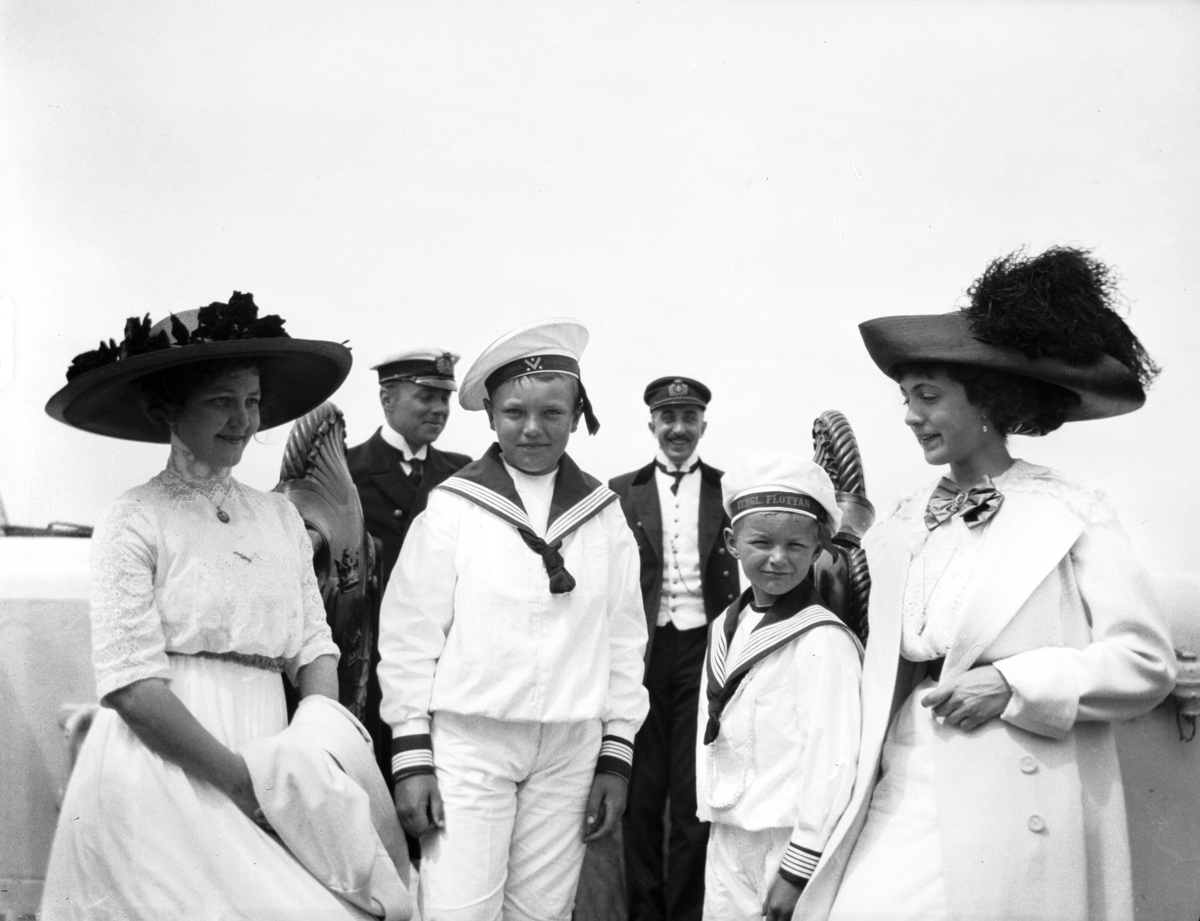 Två kvinnor med pojkar klädda i sjömanskostymer i sällskap med två marinofficerare. Bilden tagen i samband med hembygdsfesten i Borgholm midsommardagen 1912.