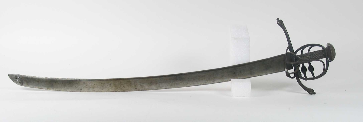 Pyramideformet knapp med strekdekor. Asymmetrisk kurvfeste med to sidebøyler( øverste avbrukket )med riflede fortykkelser på midten. mellom håndbøylen og kurvens ytterkant. Innsiden har en  sidebøyle. Kurvens basis er på utsiden en kvadratisk parérplate med to hjerteformede gjennombrytninger. På innsiden er det en klingebrekker og tommelbøyle. Opp og nedbøyde parérstenger med riflede fortykkelser på endene.
Tregrep med nyere jerntrådvikling.
Enegget krum klinge med 3 hull ipå klingspissen og en smal hulslipning på ryggsiden.Tre smedmerker på venstre side. 