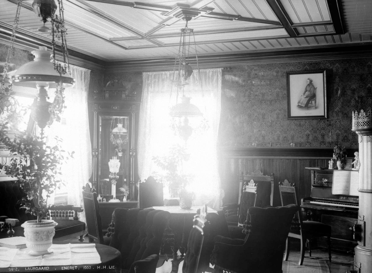 Kort: Sel Laurgaard, Interiør af salongen 18.09.1902. Bord, stoler, taklamper, rundovn, piano, stueplanter, maleri.