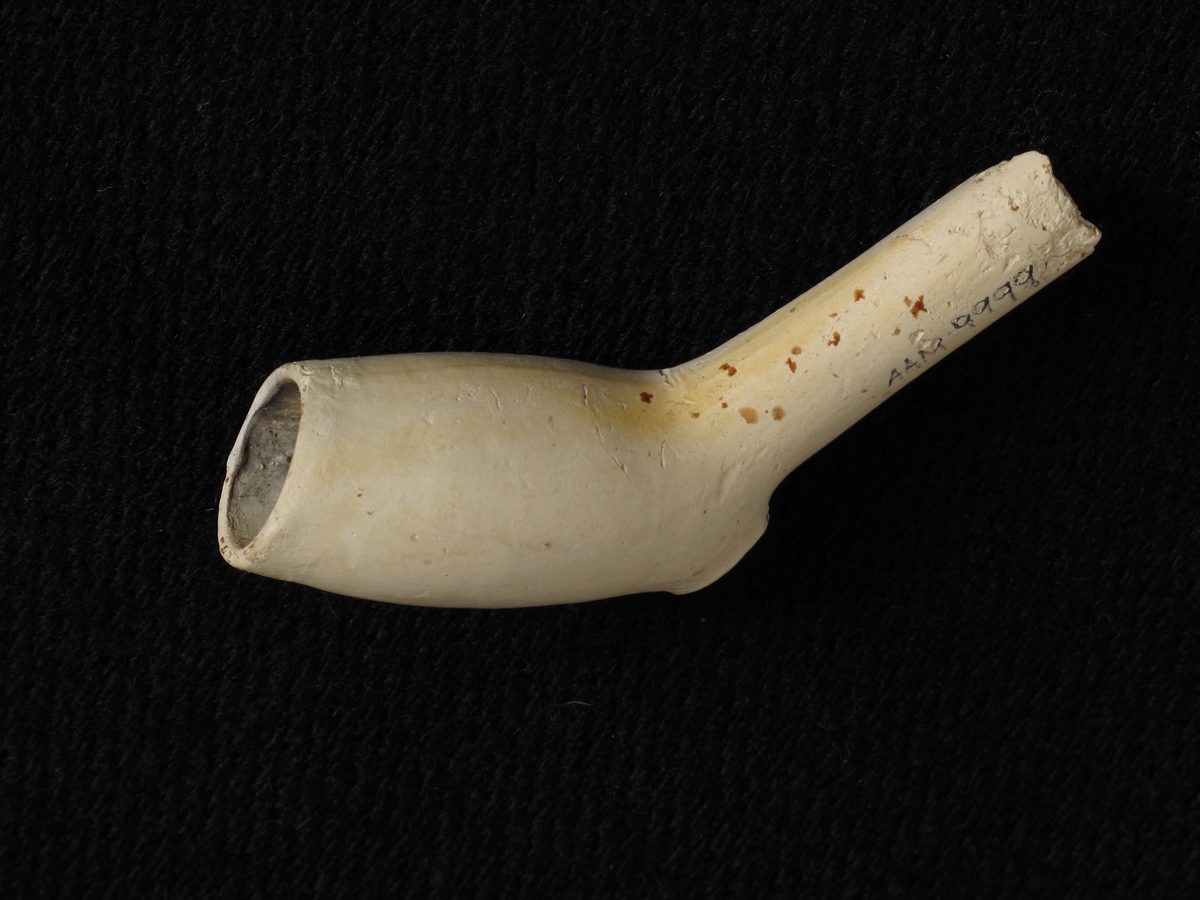 Krittpipe, hollandsk type, siste 3. del 1600 t.  Smalt hode, like bredt oppe som nede, med stor oval ståflate, tykt  kort skaft, avbrukket. Uten stempler.