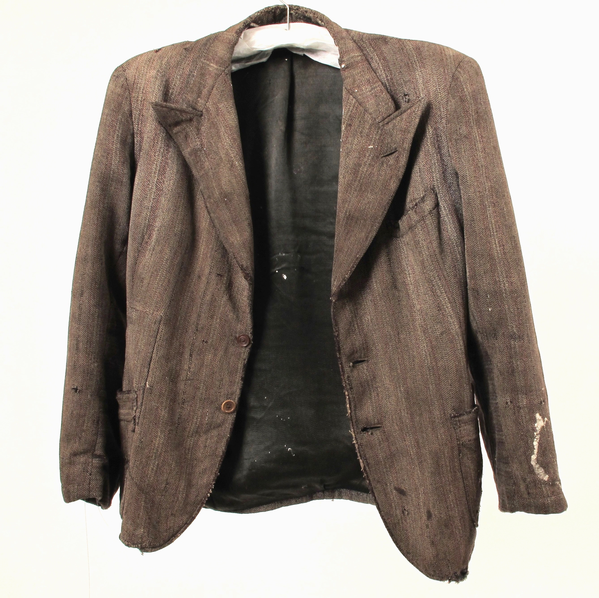 Stipet stoff, krisevare produsert under 2.verdenskrig, blanding av ull og cellull, som ble laget av cellulose. Foret var gammelt - enten noe de hadde liggende, eller sprettet av gamle klær.  Snittet er litt spesielt, trolig for å utnytte små biter stoff.