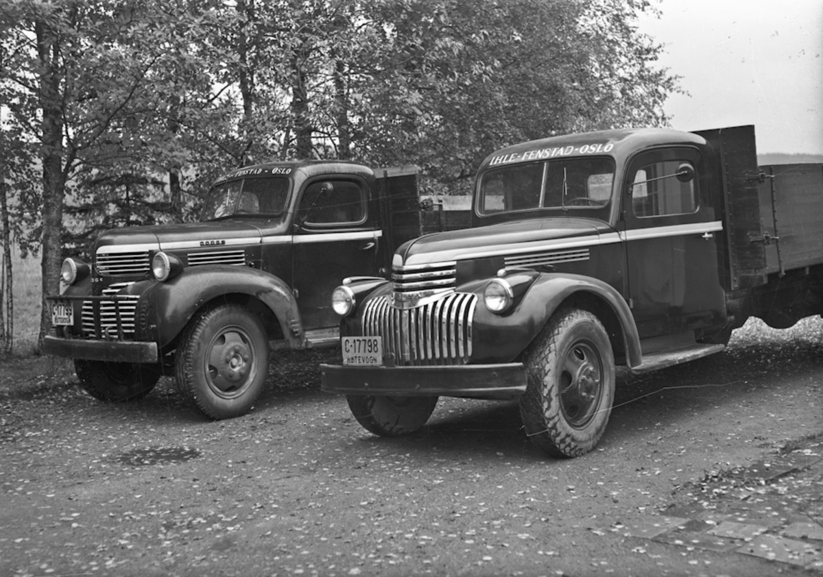 2 lastebiler. DODGE med reg.nr. C-17799 til venstre, Chevrolet med reg. nr. C-17798 til høyre. Det står skrevet IHLE – FENSTAD – OSLO på begge.
05.03.2013:
Begge disse bilene tilhørte min farfar, Rutebileier Karl Martinsen, Skogstad, 2170 FENSTAD.
Bilene gikk i godsrutetransport mellom Oslo og Fenstad og i melketransport rundt i Fenstad til Ihle Meieri. C 17799 , 1945 Dodge ble kjøpt rett etter krigen og var i bruk til utpå 60 tallet. Den ble solgt til Håvard Lunner på Frøyhov som gårdsbil. Denne bilen var en millitær modell som ble solgt som overskuddsmatriell.
C 17798, 1947 Chevrolet ble kjøpt hos Christiansen & Co i Oslo. Førerhus og lateplan ble bygget hos Sigurd Jensens karosserifabrikk på Styri i Eidsvoll.
Bilen var i bruk til på slutten av 60 tallet.
Skrevet av: Geir Martinsen
07.04.2014:
1947 Chevrolet med førerhus fra min farfar, Sigurd Jensen. Bilen tilhørte Karl Martinsen, Fenstad. Han drev godsruta Ihle-Fenstad -Kløfta-Vormsund. Registreringsmerket C-17798 var overtatt fra "Sølvbussen" som var lagd hos Sigurd Jensen-karosserifabrikk. (Etablert i 1936). Kilde: "Håndverk på hjul-Karosserifabrikker og karosseribygging i Norge". Asbjørn Rolseth.
Skrevet av: Kirsti Bokn