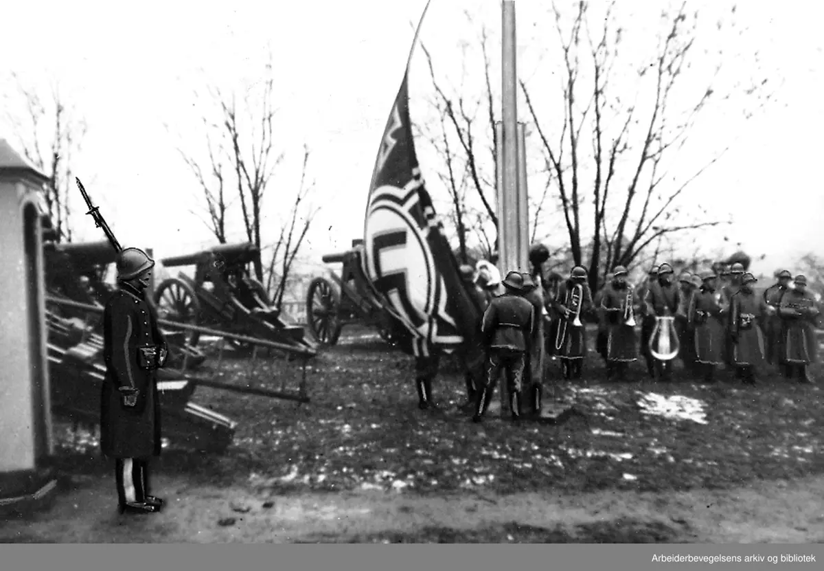 Akershus Festning 9. april 1940..Hakekorset heises av tyske soldater. En norsk gardist står fortsatt vakt..