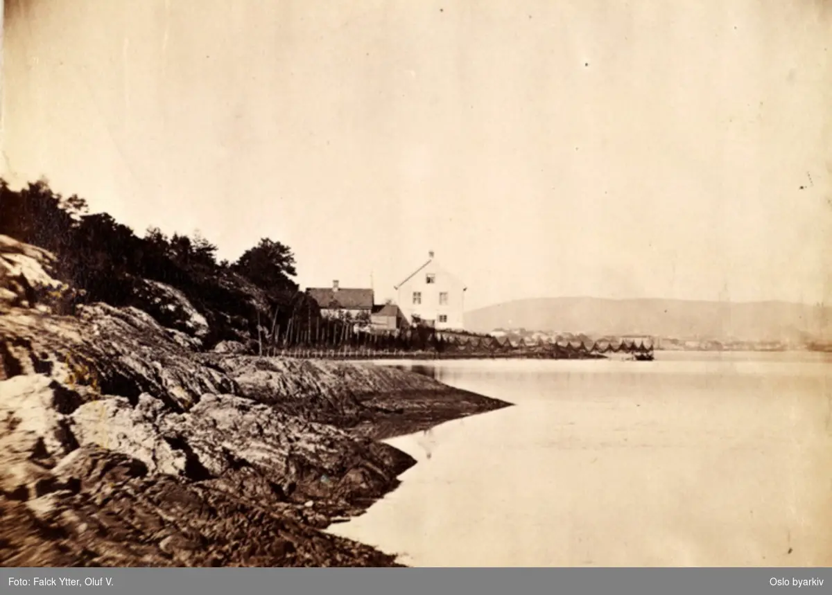 Huset på Sjursøya, på innsiden (bildet er tatt nordover). I bakgrunnen sees husene i Kongshavn, og kanskje også i Oslo. Garn til tørk ved stranda.