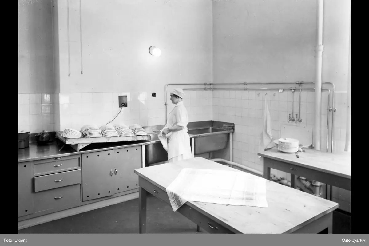 Kvinne som vasker opp, oppvask. Møllergatens skoles utvidelse, 1933 (albumtittel) (Møllergata skole)
