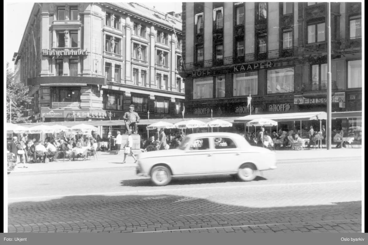 Uteservering ("Dasslokket") på Stortings plass utenfor Tostrupgården. Parasoller. Christian Krohg-statuen. Centralgården bak til venstre. Karl Johans gate i forgrunnen. Lille Grensen.