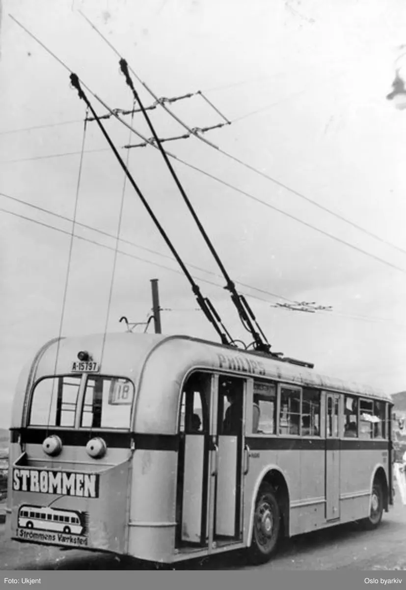 Trolleybuss i Valhallveien ved ustikten i svingen rett nedenfor Ekeberg camping. Vogntype E-41. Reklame for Strømmens verksted.