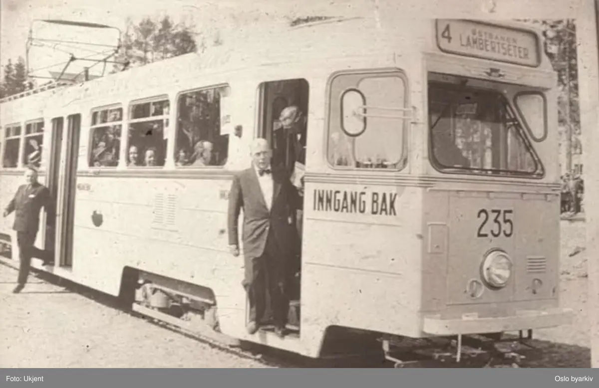 Oslo Sporveier. Trikk motorvogn 235 type Høka MBO linje 4, på Lambertseterbanens åpningsdag 28. april 1957. Åpningstoget har kommet fram til endeholdeplassen og Brynjulf Bull og Frederik Schreiner (i fordøra) og Oslo Sporveiers direktør C. F. Mathiesen (bak) går av.