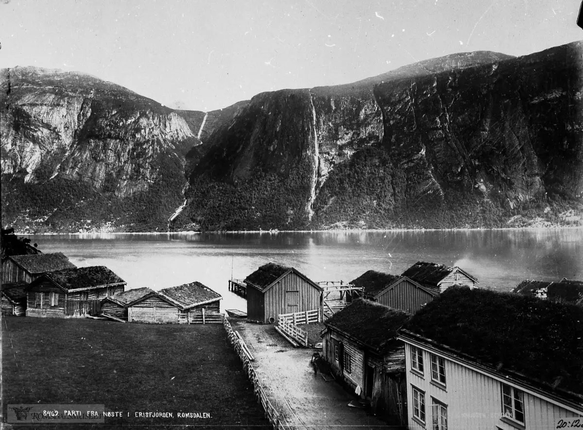 Nauste sett frå "Hotel Eikisdal". Det kvite huset tilh.Nils J. Næss (hotelleigar) og det andre var stua til Brit Kofoed (Skul-Brit) f. 1821. Sjå "Molde og Romsdals Turistforenings Årbok "1979 s.157-165. Knudsen nr. 8469...