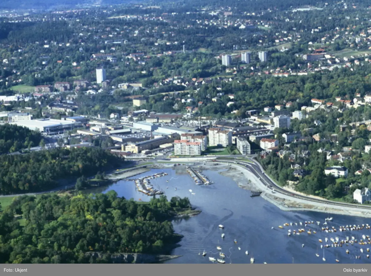 Frognerkilen med Frognerstranda. Boligblokker, Industrområde og messehaller bak. Bebyggelsen på Ullern og Montebello i bakgrunnen. (Flyfoto)