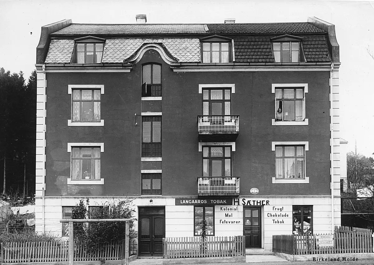 Haagensenhuset..H.Sæters kolonial. (Ute på Røysand) Matr nr 301: Molde. 1935...Harald Sæter, stesønn av havnebetjent Harald Haagensen og eier av bygningen. Harald Sæter drev butikk der til 1942-1943. Da skjedde det en episode i butikken hvor Harald Sæters kone Anna Kristine holdt på å bli drept av en tysk soldat. Bak et forheng hadde butikken gjemt tobakk, men forhenget var ikke trukket for skikkelig da den tyske soldaten med gevær kom inn. Dette visste ikke Anna Kristine og nektet blankt på at butikken hadde tobakk. Den tyske soldaten så den gjemte tobakken og holdt bajonetten mot Anna Kristine og forlangte tobakk, hvis ikke ble hun drept...Kort tid etter denne episoden la Harald og Anna Kristine ned butikken og flyttet til Bolsøya, og senere til Kristiansand...Damen vinduet oppe til høyre, er mest sannsynlig Asta eller Ebba Haagensen.