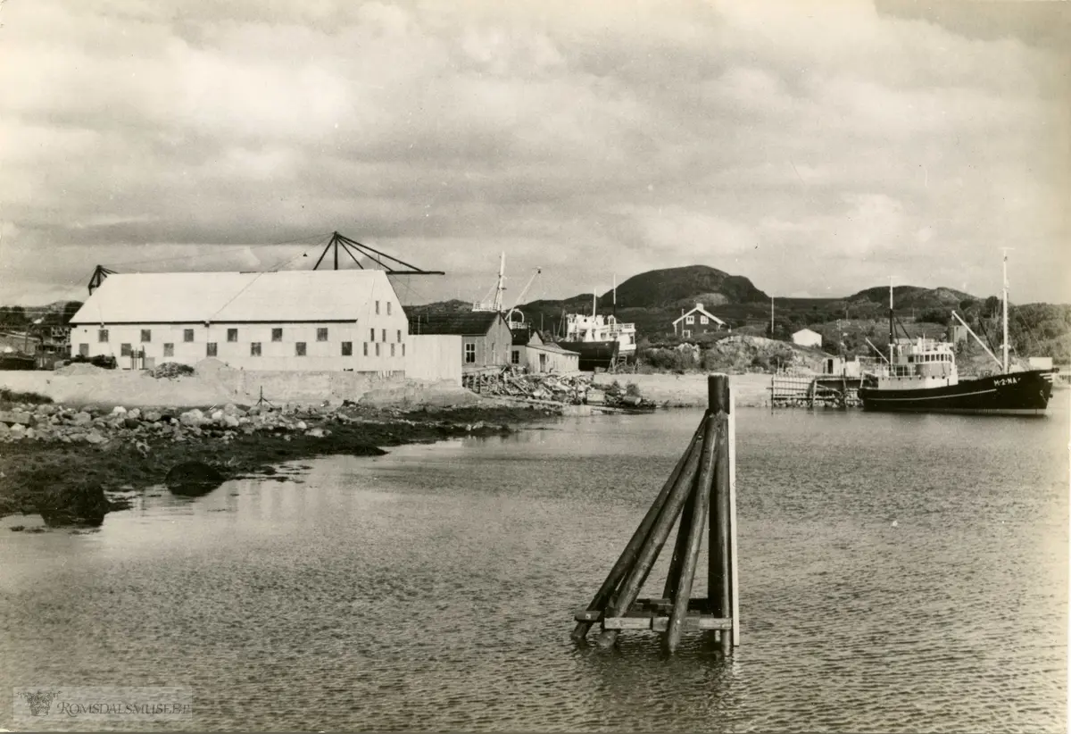 Aukra Bruk A/S.Båten som ligg ved kaia er M/K Storsund bygg nr 2 frå Aukra Bruk AS. Byggeår 1955, Reiarar Berdon og Erling Tangen. Biletet er teke medan båten framleis var merka med NA for Nordaukra, noko som seinare vart endra til AK for Aukra.