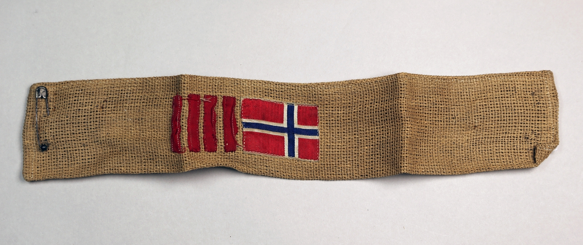 Norsk flagg og fire røde render er sydd på