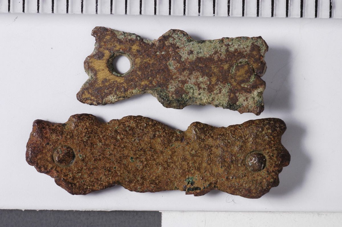 MALV: A: 12*5 B: 18*5, 5 MM, A: BÅNDFORMET MED UREGELMESSIG KANT. 2 HULL ETT MEDNAGLEFRAGMENT. B: BÅNDFORMET MED URGELMESSIG KANT. 2 HULL MED NAGLEFRAGMENT. 