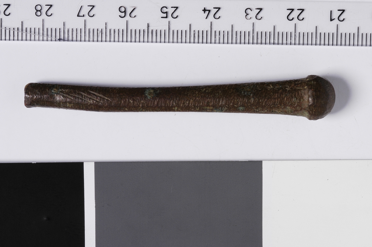 MALV: SE BESK., L. 73 MM, SKAFTETS B. 6 MM, ENDEDIAMETER 10 MM. SKAFTET HAR TILNÆRMET OVALT TVERRSNITT, AVBRUKKET I ENE ENDEN, OG TIL-NÆRMET KULEFORMET AVSLUTNING I ANDRE. 