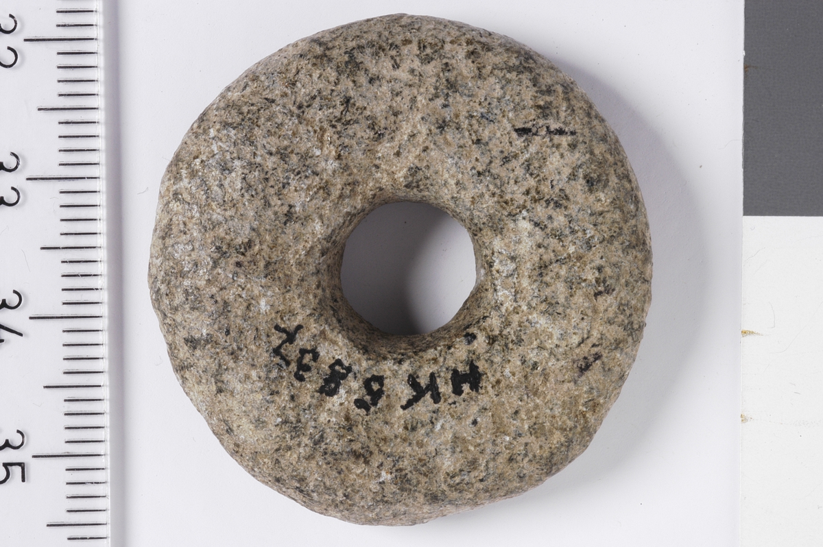 Spinnehjul i stein med flat over- og underside, og buede kanter.