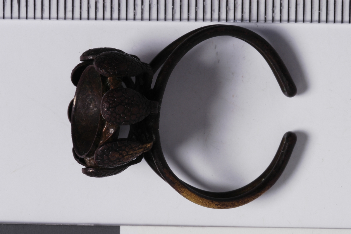 MALV: D. 23, 5 MM, SELVE RINGEN ER ÅPEN OG LAGET AV EN DOBBELT-BRETTET1, 5 MM TYKK TRÅD. 8-BLADET KRANS RUNDT ET STENFESTE. 