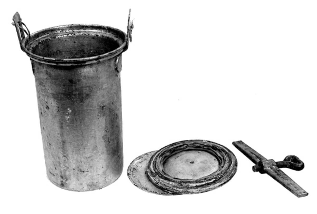 Hermetiseringsbeholderen er laget av fortinnet jern. Den er sylindrisk, 18,5 centimeter høy («ørene» som lokkene festes i er ikke inkludert i dette målet) og har i hovedsak en diameter på 10,4 centimeter. Overkanten er imidlertid utkraget. Her er diameteren 12,6 centimeter. Når beholderen fylles til like oppunder den utkragete overkanten kan den romme drøyt 1,4 liter. Ved overkanten, diametralt plassert i forhold til hverandre, er det påklinket og fastloddet to oppoverrettete «ører» med gjennombrutte, rektangulære hull for feste av lokk og forseglende pakning. Beholderen har to lokk. Det underste har er lagd av forholdsvis tynt blikk og har en diameter på 10,9 centimeter. Midt på denne plata er det en skålformet forsenkning med cirka 30 centimeters diameter. Ytterkantene er noe oppovervendte. Oppå dette lokket legges en pakning, en cirka 2,3 centimeter bred gummiring med en ytre diameter på 11,9 centimeter. Oppå pakningen legges et ytre lokk, lagd av ei 1,9 millimeter tjukk plate med 11,8 centimeters diameter. Også her er den midtre delen noe forsenket. Mot ytterkanten er det påseveiset ei lita handtaksbøyle. Lokkene og pakningen festes ved hjelp av ei 16,5 centimeter lang jernstang der det er plassert en nedoverrettet vingeskrue på midten. Stangas ytterender stikkes inn i hullene i de nevnte ørene øverst på beholderen. Deretter strammes skruen, slik at lokkene og pakningen presses hardt ned mot den utkragete overkanten på beholderen.