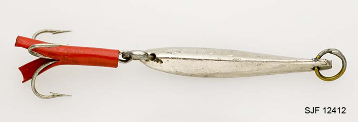 Svakt bøyd trekantet, bananformet, pilk med treblekrok (trippelkrok). Trippelkroken er festet til en ring som ser ut til å være loddet. Kroken er trukket med en plaststrømpe (gummislange) som er splittet mot krokspissene. Pilken har en ring for senefeste i bakkant. Uten at det er bekreftet, antas det at pilken er en såkalt "Svenskepilk".