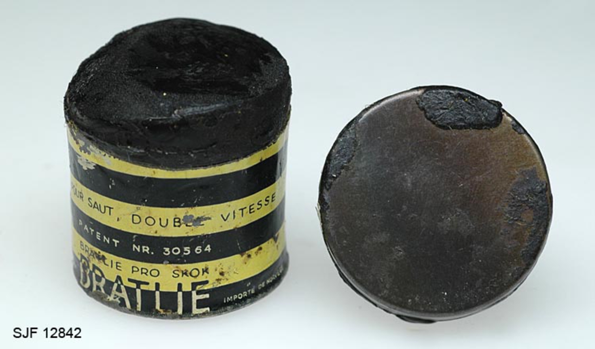 Boksen med skismurning har sylindrisk form. Den består av en metallsylinder og et lokk. Utenpå metallsylinderen er det påklistret en etikett hvor det bl. a er bilde av en skihopper som utfører et svev (øvrig informasjon fra etiketten er ført inn i feltet for påført tekst). 
Teksten som er påskrevet øverset på boksen er nesten helt borte, slik at det er umulig å tyde hva som har stått der. Etter hvert som man har brukt smurning, har det vært nødverndig å rive av deler av boksen, og dermed har deler av den påførte teksten på boksen fulgt med. 