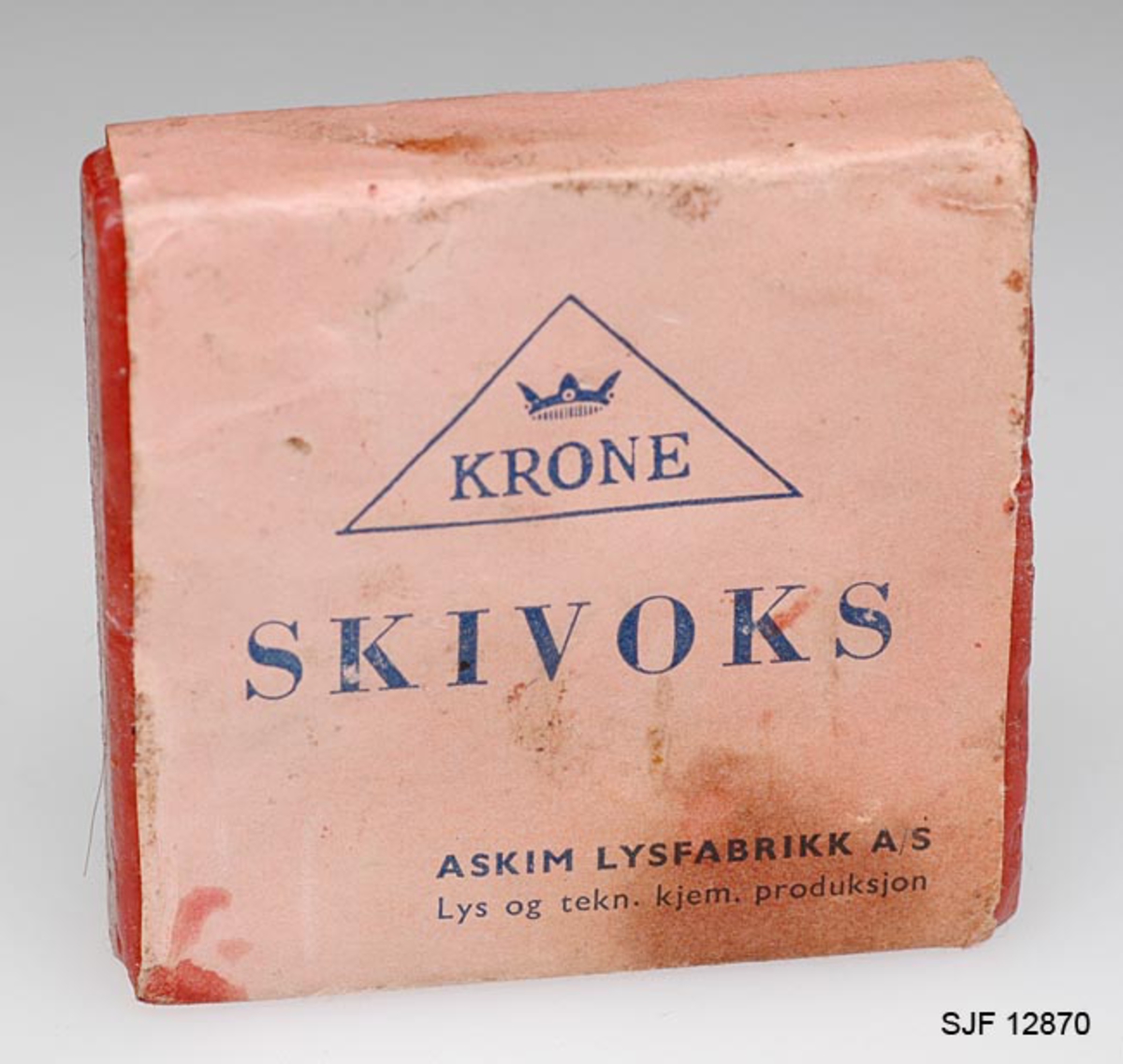 Gjenstanden består av et kvadratisk stykke med skismurning emballert i et papiromslag. Omslaget har en rekke påskrifter i blått. (Avskrevet i eget felt i Primus. ) På papiromslaget gjenfinnes firmates logo, varemerket, som består av en kongekrone og teksten KRONE omsluttet av en trekant. 
