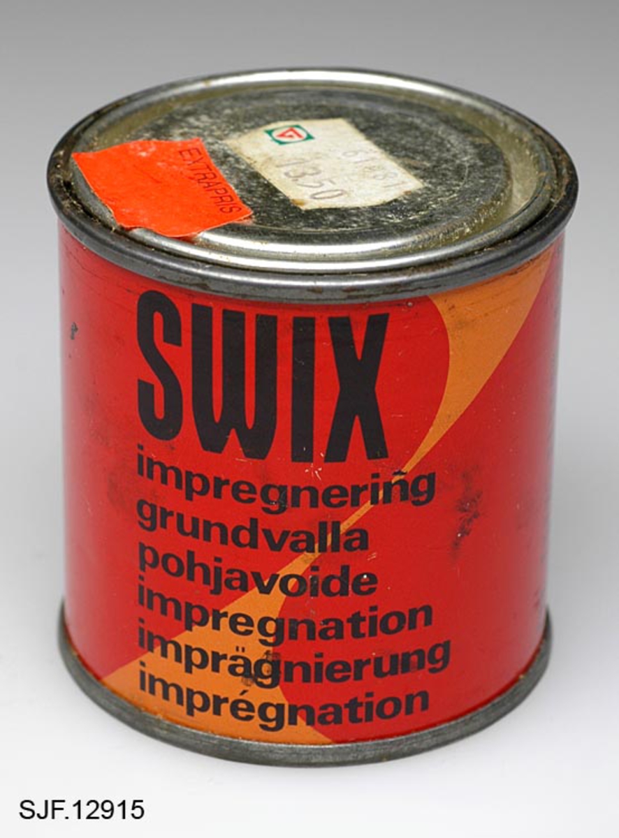 En boks, sylindrisk metallbeholder, med syntetisk impregnering for treski. Impregneringen holder vann og fuktighet borte fra skiene og gir bedre feste for smurningen som påføres etterpå. Denne impregneringen brennes inn i tresålen med smørelampe.  På metallbeholderens lokk er det påklistret to prislapper. Den ene står det "260111982 13. 50" på, den andre står det "extrapris" på. 
Det er noe innslag av rust der beholderen er skjøtet sammen. 