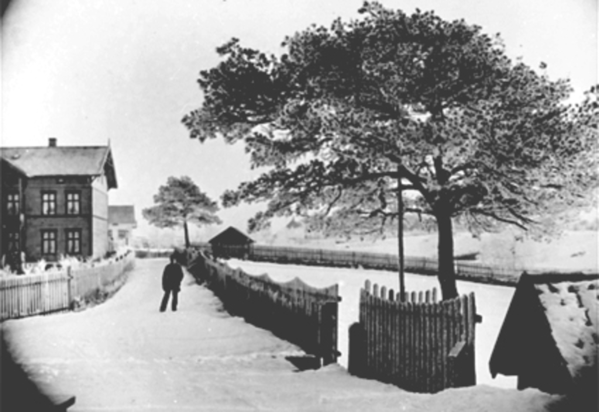 Hamar, Parkgata 34, huset til stasjonsmester Christian Fredrik Lund til venstre der Statens hus ligger i dag. Jenbanebryggeriets iskjeller til høyre (Parkgården sykehjem i dag) . Vinter, stakitt.  Ved senere regulering av Parkgata i 1895 ble hus nr 34 liggende midt i gaten, da måtte snus 90 grader så det lå langs den nye Parkgata. Prestefamilien Erichsen bodde her ved folketellinga i 1885,