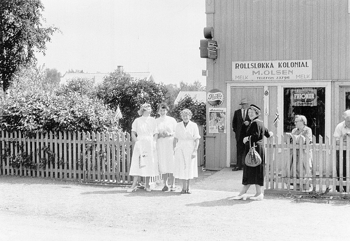 ROLLSLØKKA KOLONIAL. BUTIKK.  BETJENING OG FOLK FORAN, FRA VENSTRE: LAURA BEKKELUND, SIGRUNN RØNNINGEN, HILDA OLSEN ( f. Nilsen), VED GJERDET: VALBORG SVAANAA, JOHANNE OLSEN OG INNEHAVER: MARTIN ALBERT OLSEN (17. 09. 1885-24. 09. 1968), MANN I BAKGRUNN: THORVALD SVAANAA, HOLSETGATA 79, HAMAR.